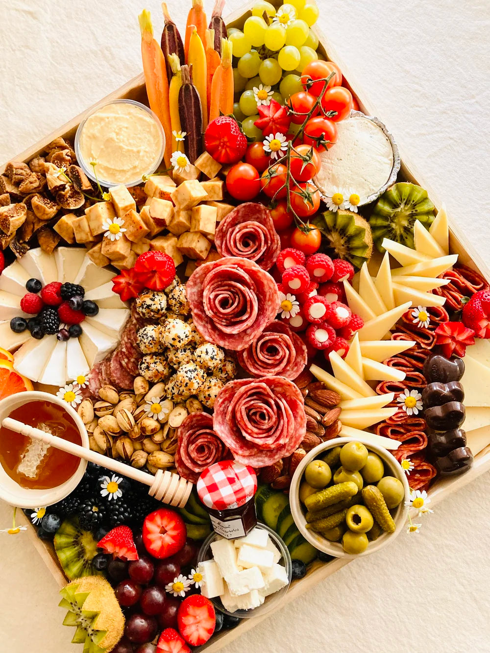 Assorted charcuterie board with fruits, meats, and cheeses on a wooden board.