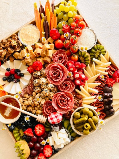 Assorted charcuterie board with fruits, meats, and cheeses on a wooden board.