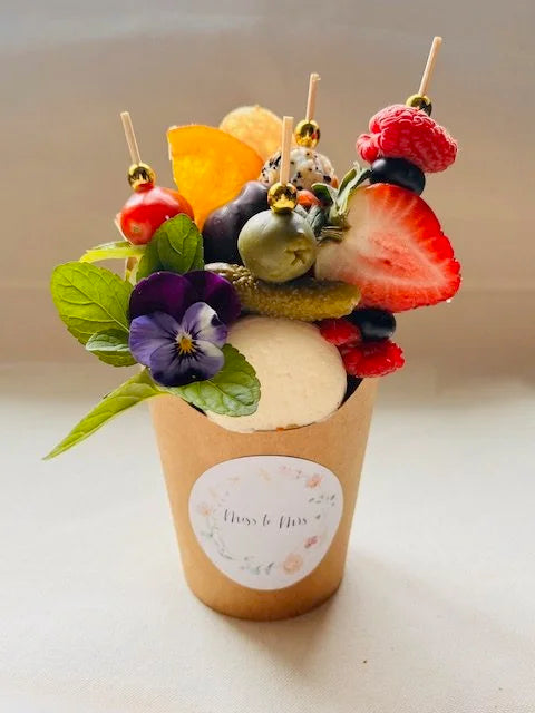 Fruit skewer dessert in a cup with a visible brand label on a light background