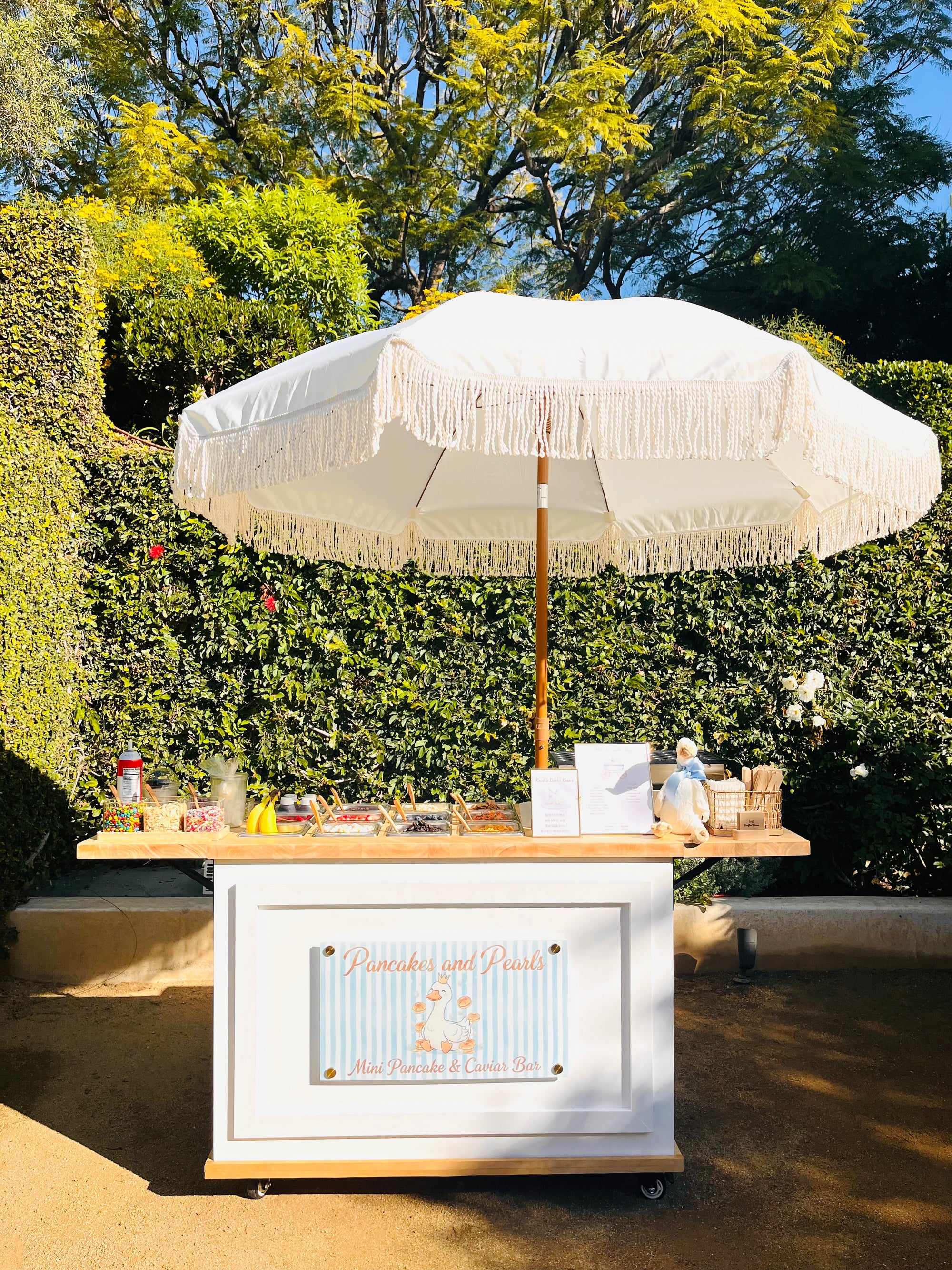Outdoor cart with a large white umbrella in a garden setting
