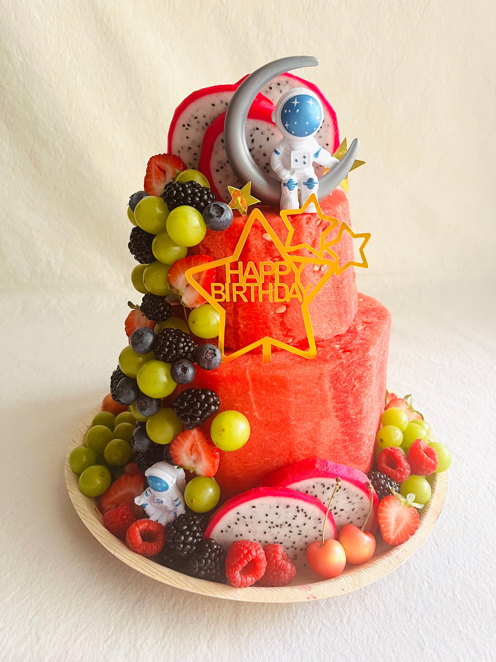 Fruit-themed birthday cake with colorful decorations on a white background
