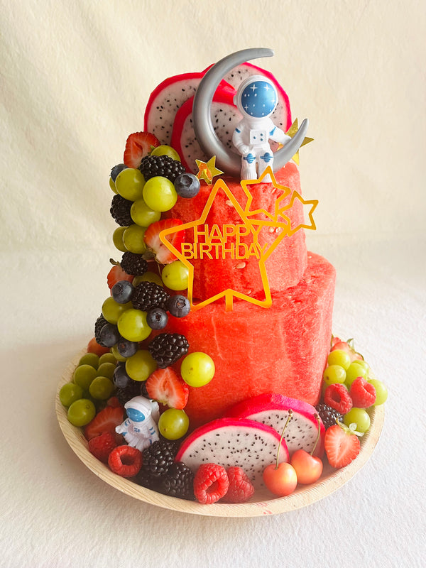 Fruit-themed birthday cake with colorful decorations on a white background